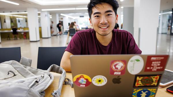 Student smiling over a laptop